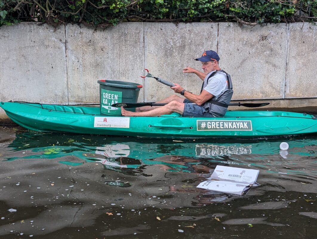 Tobi Hatge, a manager at SUP CLUB Hamburg, collects trash along the Isebekkanal.